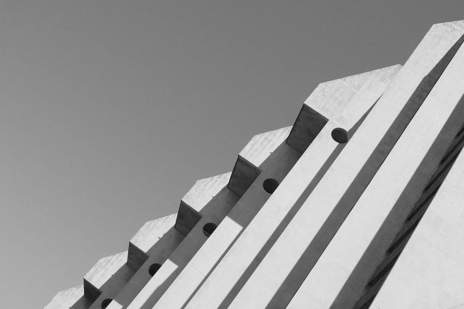 A black and white architectural photo of modern geometric concrete structures with circular cutouts.