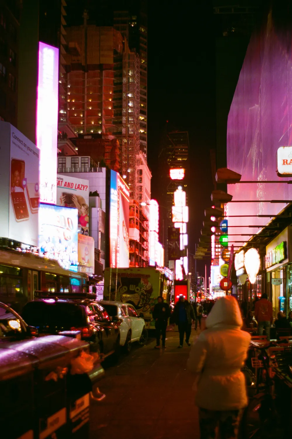 A vibrant night street view of New York City surrounded by glowing neon billboards and illuminated storefronts.