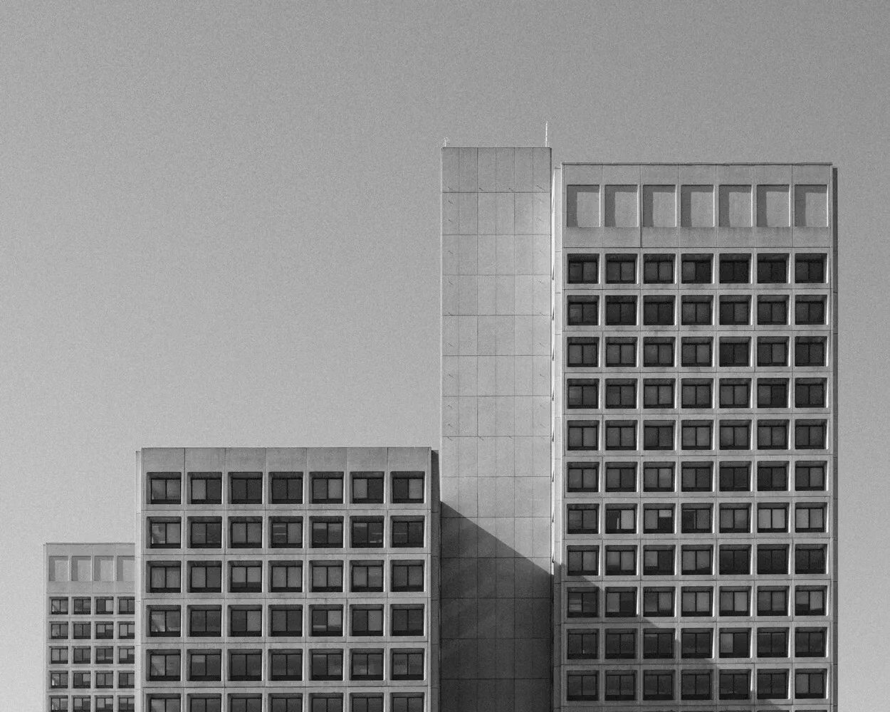 A black and white architectural shot highlighting the geometric windows of brutalist concrete buildings.